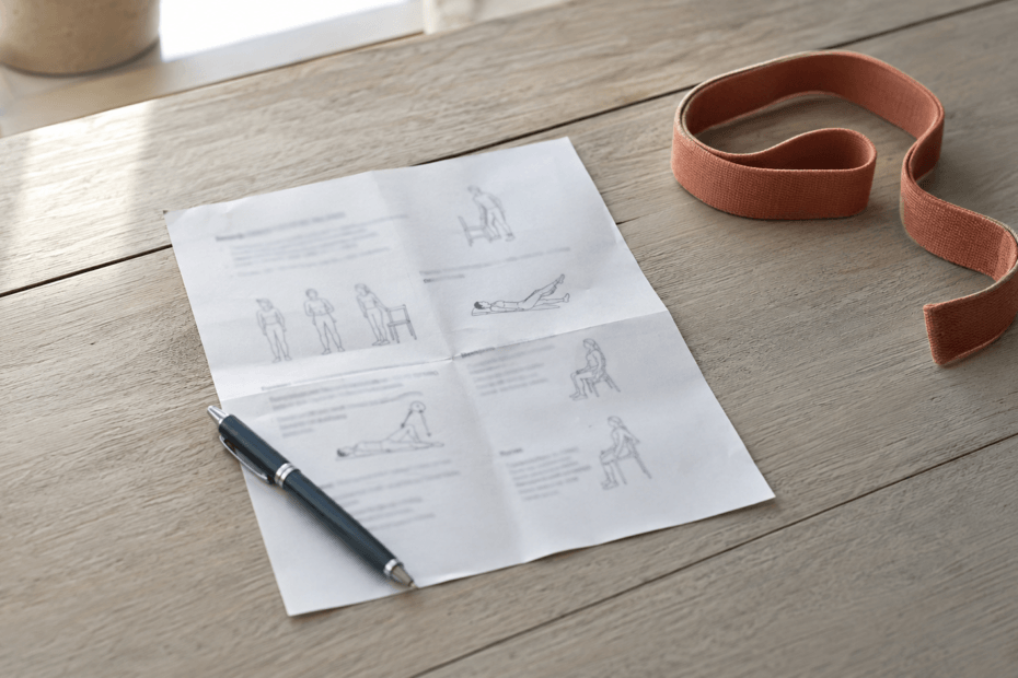 A printed exercise sheet and resistance band on a kitchen table — home exercises after hip replacement surgery.